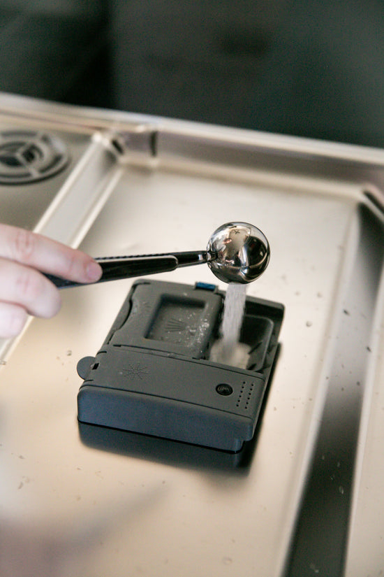 Powder Dishwasher Detergent measured with a reusable stainless steel scoop into a dishwasher detergent dispenser.