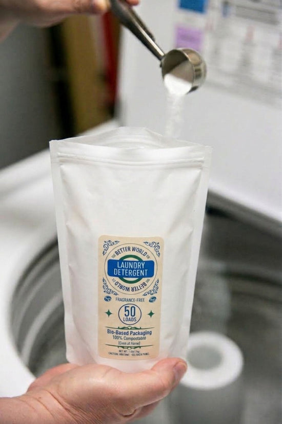 Powder Laundry Detergent measured with a stainless steel scoop above a 50-load home-compostable refill pouch.